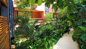 A narrow pathway flanked by lush greenery and a building with a red facade. - Mi Querido Tulum Apt with Pool-View (Tulum)