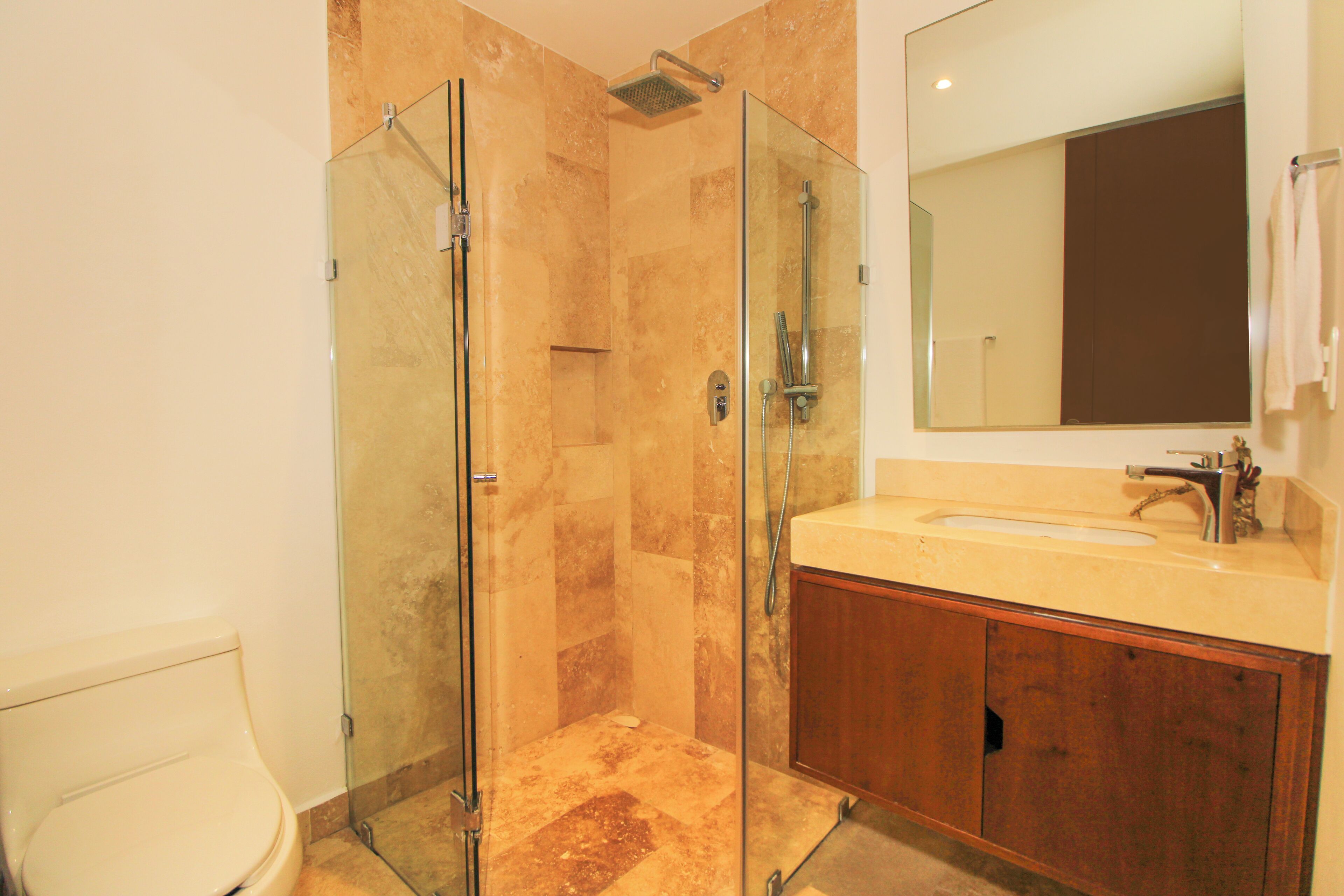 Une salle de bain avec une douche à parois de verre, un lavabo avec un miroir et des meubles en bois.