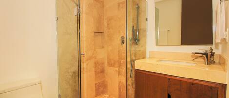 Une salle de bain avec une douche à parois de verre, un lavabo avec un miroir et des meubles en bois.