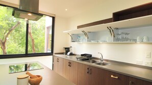 A modern kitchen with a large window, wooden cabinets, a stainless steel sink, and a countertop with a tea set. - Mi Querido Tulum Apt with Pool-View (Tulum)