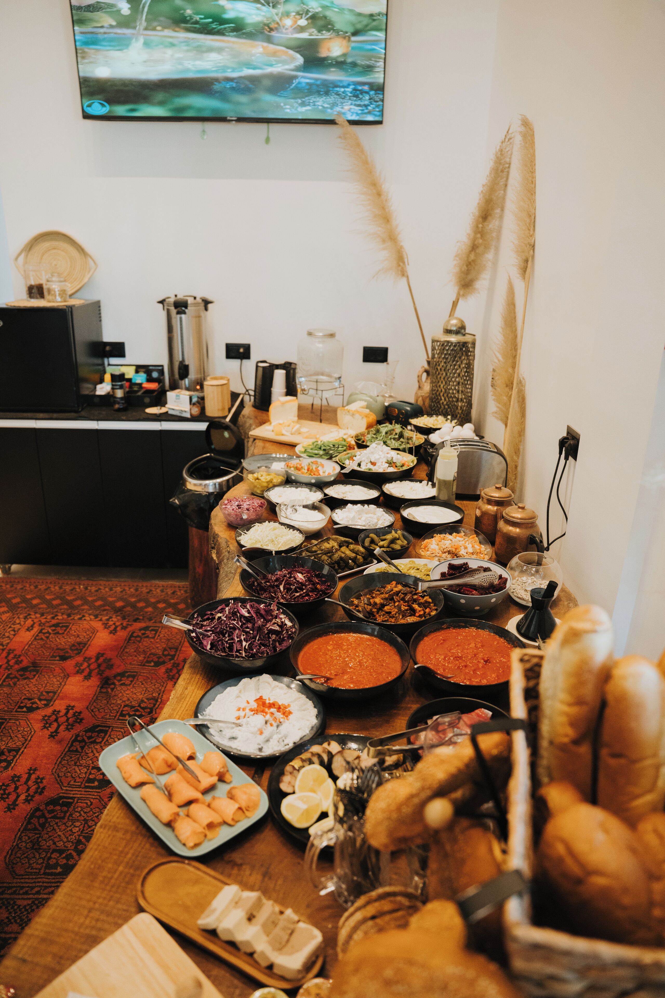 A buffet table with various dishes and a television mounted on the wall.
