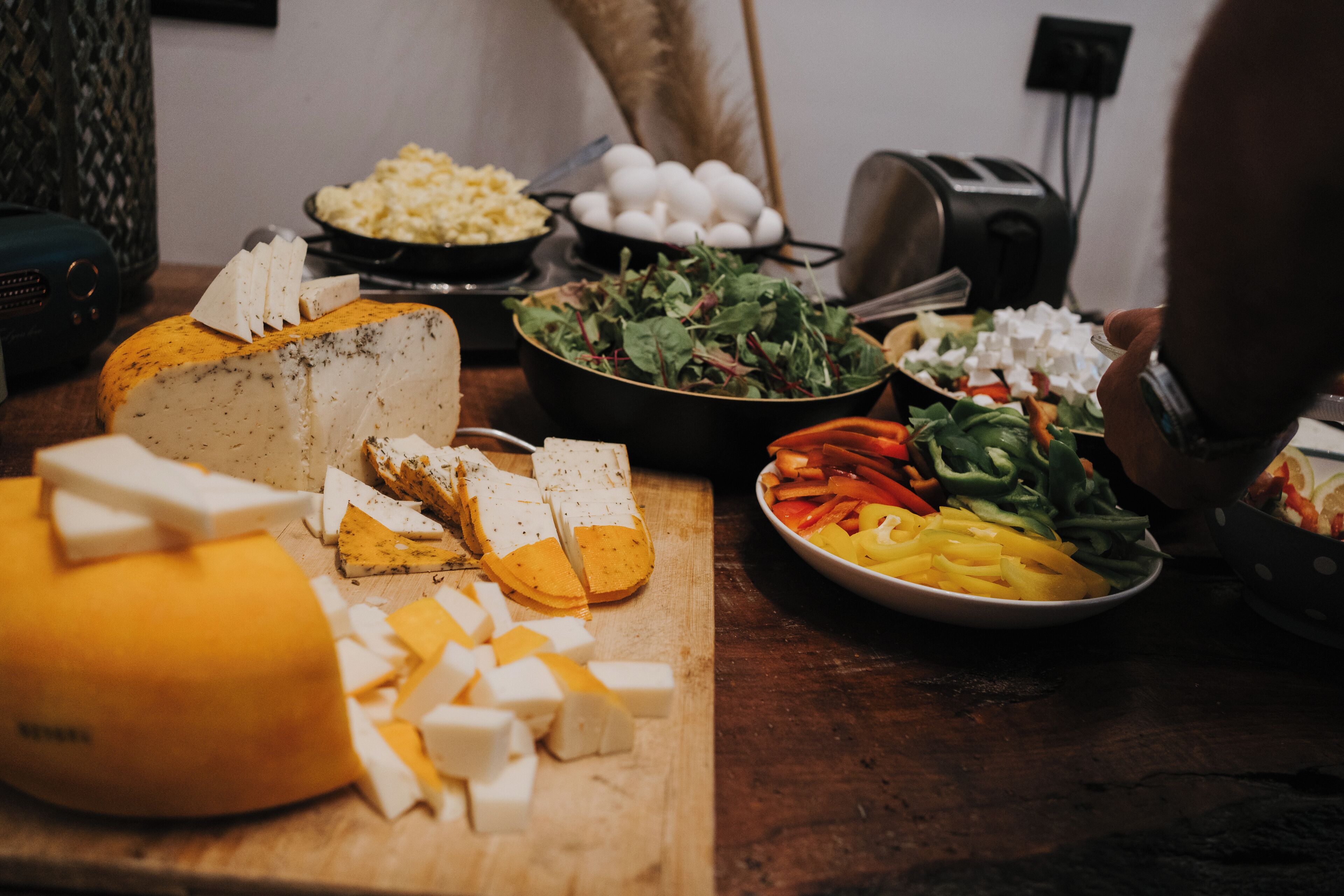 A cheese platter with various cheeses and accompaniments on a wooden table.
