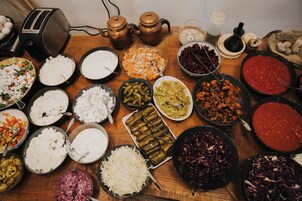 A variety of dishes on a wooden table, including salads, rice, and other foods.