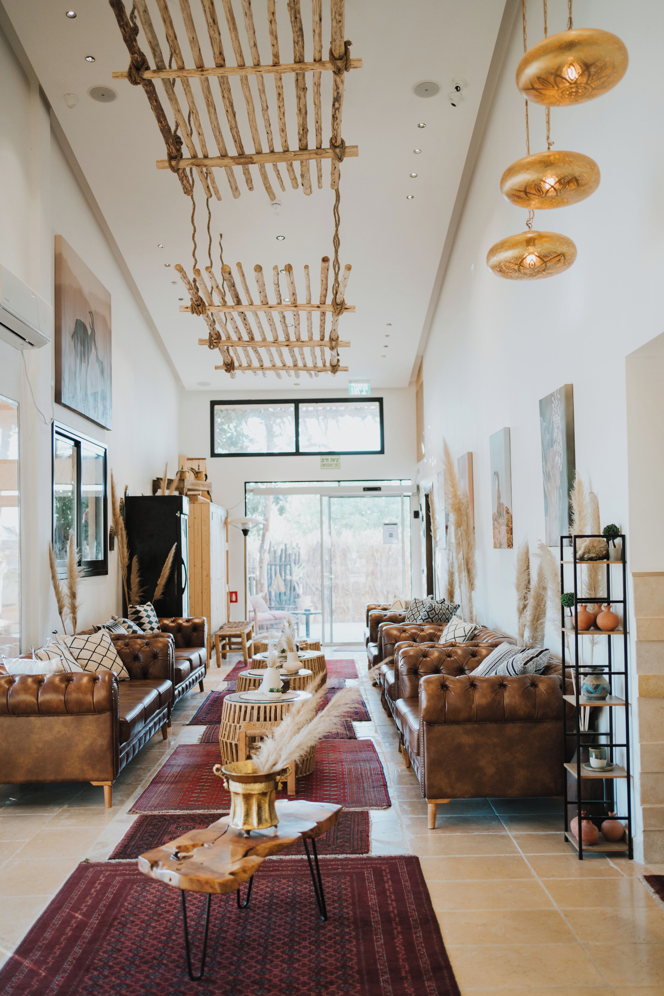Un salon spacieux avec des canapés en cuir, une table basse en bois et un luminaire au plafond au design original.