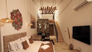 Une chambre à coucher avec un lit, une télévision, un escalier et un mur en pierre.