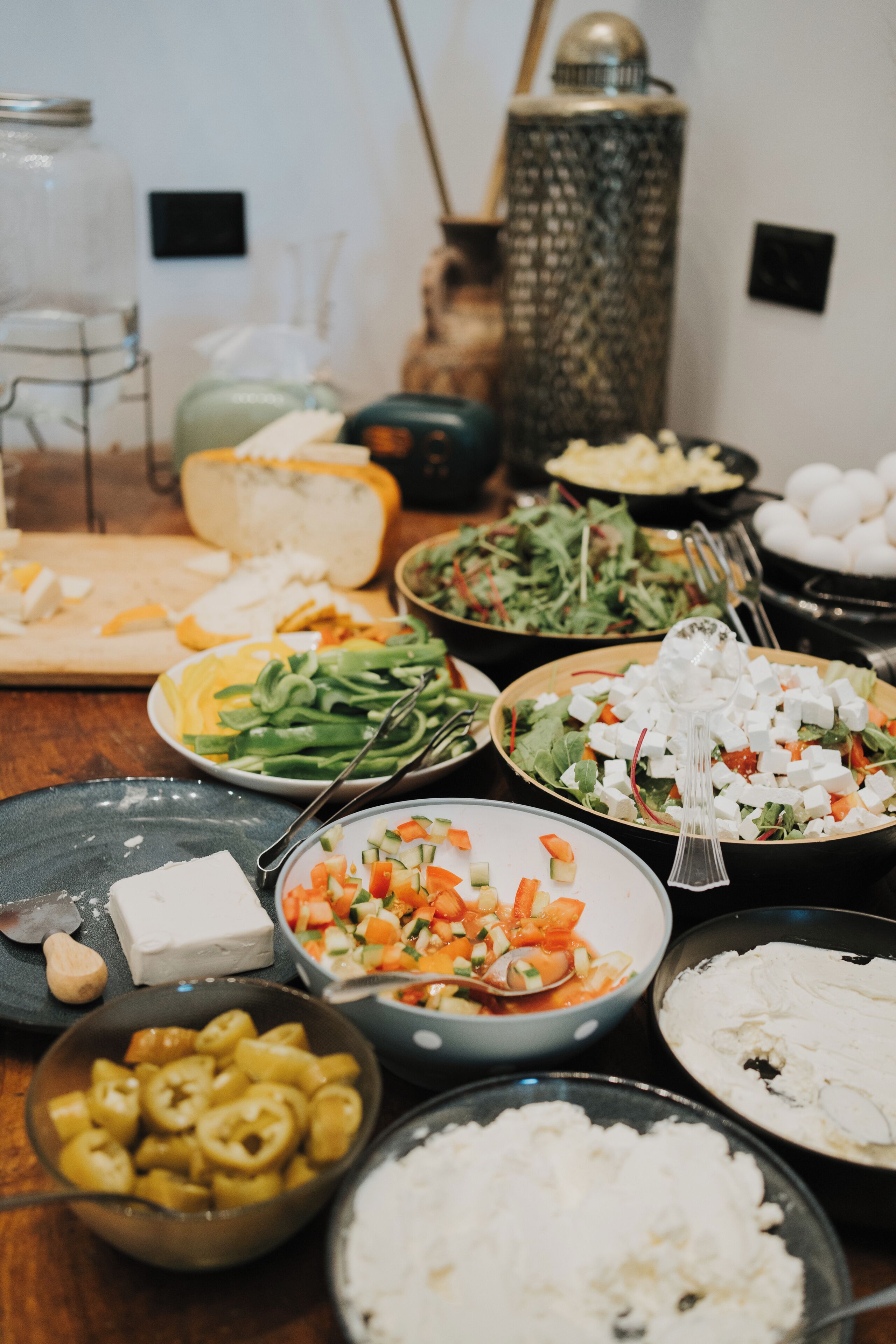 A variety of dishes on a table, including salads, cheeses, and other foods.