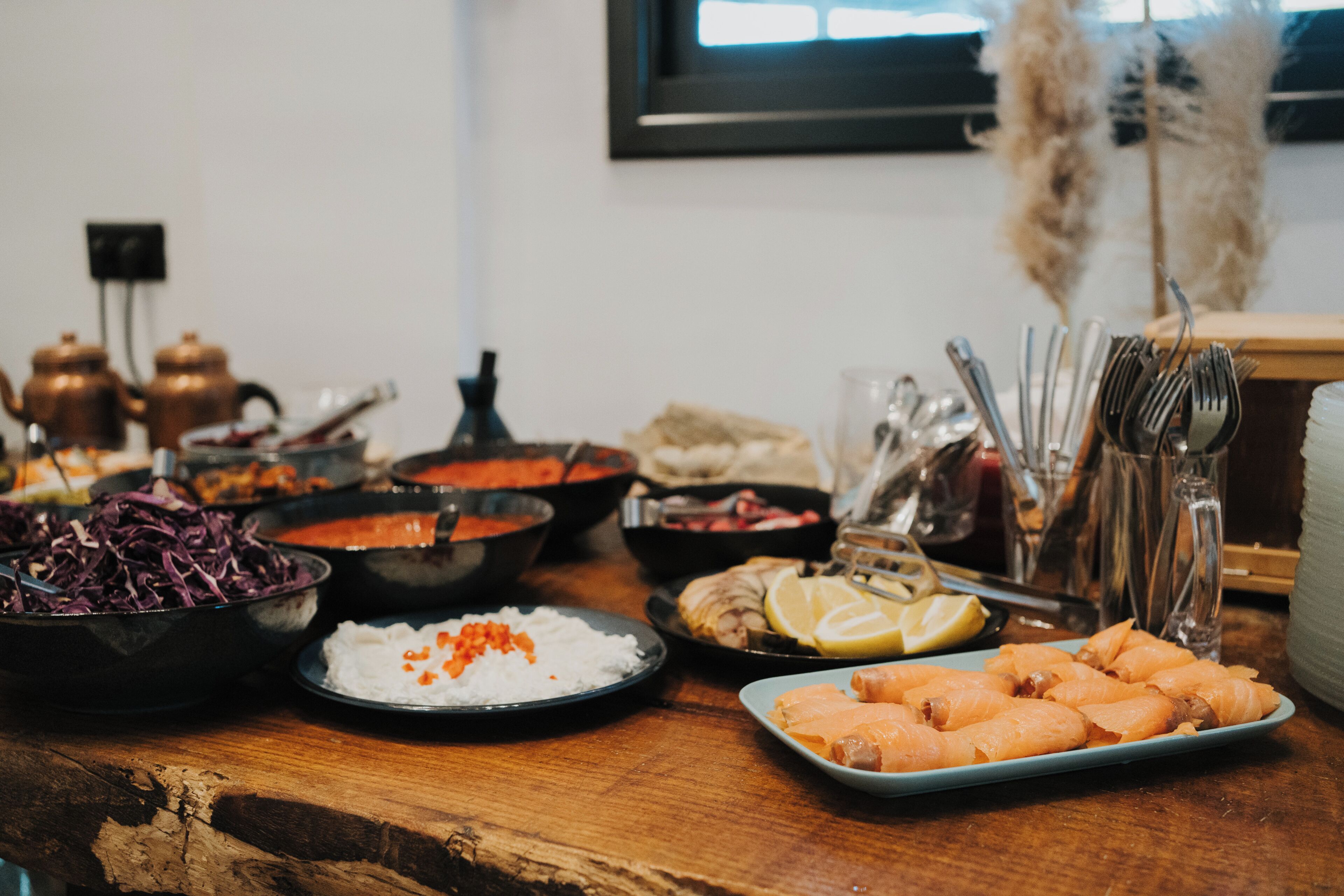 Una mesa con diferentes alimentos y utensilios, incluyendo tazones con comida, platos de comida y un juego de tenedores.