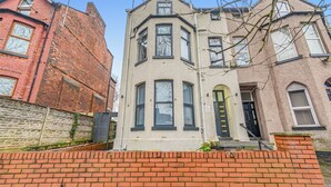 A corner building with a brick facade, a bay window, and a door with a yellow handle. - Modern 1 Bed - Near City Centre  (Manchester)