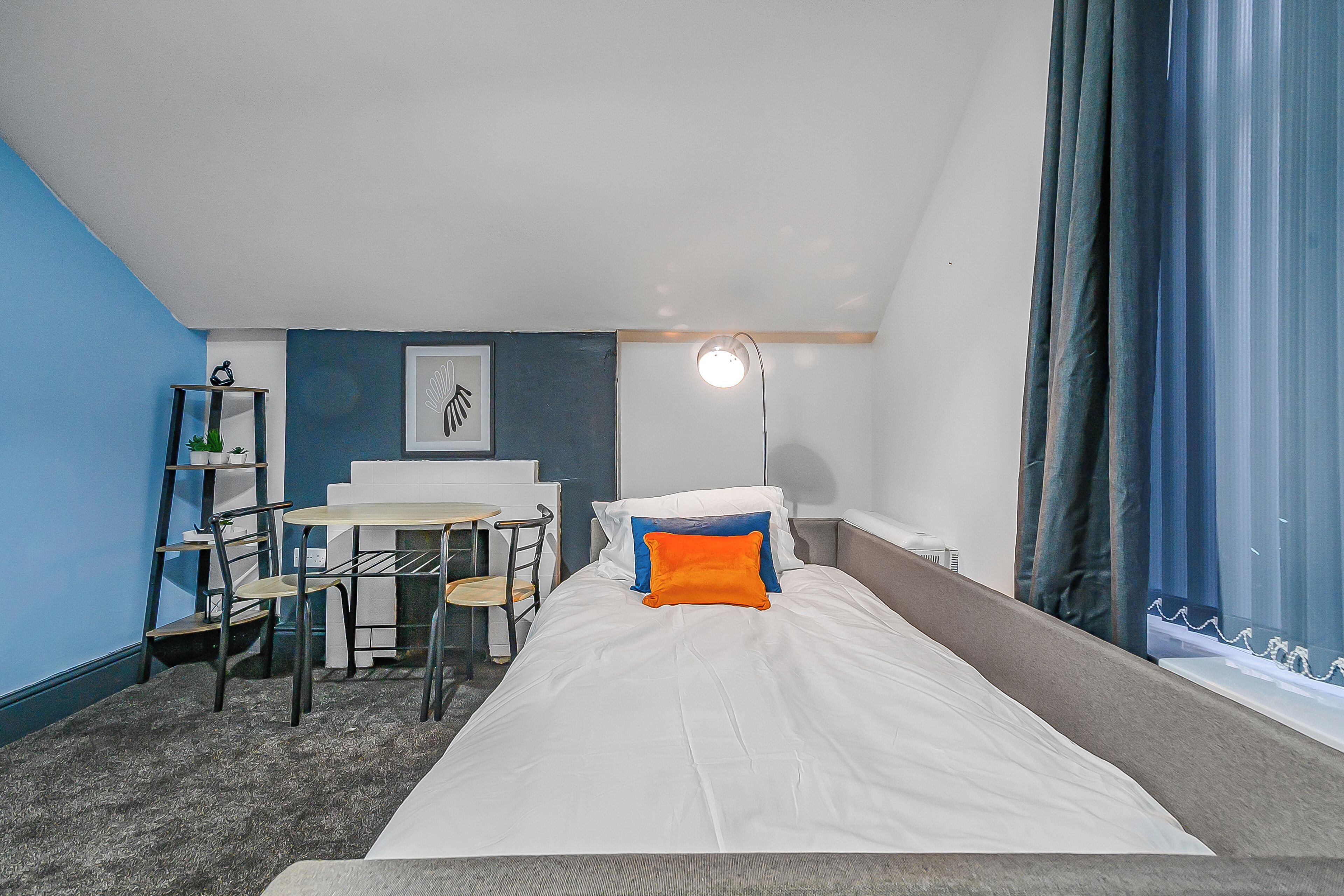 Une chambre d’hôtel de taille réduite, comprenant un lit, un bureau et une chaise.