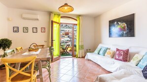 Un coin repas avec une table et des chaises en bois, un canapé agrémenté de coussins à motifs et un tableau accroché au mur.