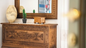 Une commode en bois ornée de sculptures complexes, un vase et un petit cactus posés sur le dessus.