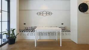 Una habitación moderna con un banco blanco, una mesita pequeña y un adorno de pared decorativo.