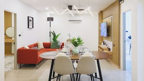Un comedor moderno con un sofá rojo, una mesa de madera dispuesta para cuatro comensales y un televisor montado en la pared.