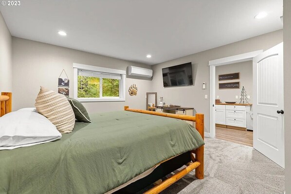 A bedroom with a bed, a desk, a television, and a window with a view of greenery. - Cozy 2-bedroom LAKE HOUSE in charming Cougar with cool AC (Cougar)