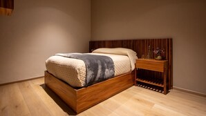 A modern bedroom with a wooden bed, a nightstand, and a built-in shelf. - Hotel Bravo (Valle de Bravo)