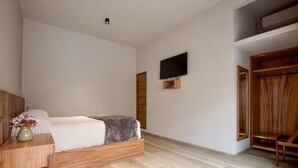 A bedroom with a bed, wooden bedside table, TV mounted on the wall, and a wardrobe. - Hotel Bravo (Valle de Bravo)