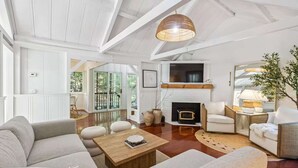 Un salon spacieux avec une cheminée, des murs blancs et un plafond haut.