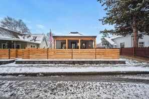 A building with a porch, a flag, and a wooden fence. - Central Coeur d'Alene Home w/ Patio & Easy Access to Lake (Coeur d'Alene)