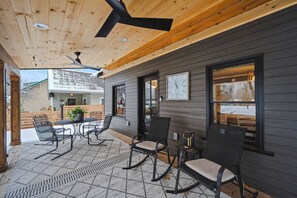 Eine überdachte Terrasse mit Deckenventilator, Holzwänden und einem Essbereich mit Stühlen und Tisch.