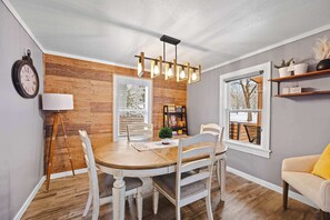 A dining area with a wooden table and chairs, a modern chandelier, and a bookshelf. - Central Coeur d'Alene Home w/ Patio & Easy Access to Lake (Coeur d'Alene)