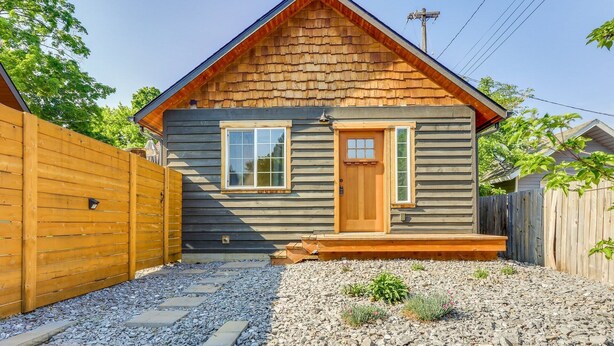 Une petite maison en bois avec un toit à pignon, une porte d’entrée et deux fenêtres.
