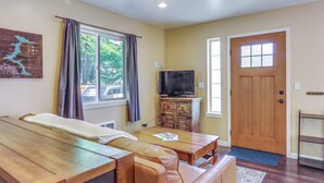 Une pièce chaleureuse avec une table en bois, un canapé en cuir et un téléviseur posé sur un meuble.