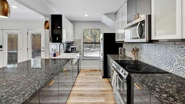 Eine moderne Küche mit Granit-Arbeitsplatten, Edelstahlgeräten und einer strukturierten Spritzschutzwand.