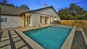 Ein Haus mit Steinverkleidung, einem Schwimmbad und einer Holzterrasse.