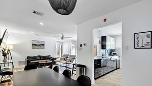 Ein modernes Wohnzimmer mit Esstisch, Sofas und einer Küche im Hintergrund.