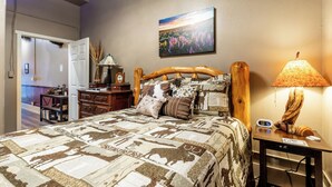 Une chambre à coucher avec un lit, une table de chevet, une lampe, une horloge et un tableau au mur.