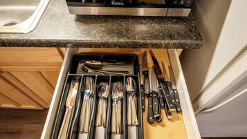 A kitchen with a granite countertop, a dishwasher, and a drawer organizer with utensils.