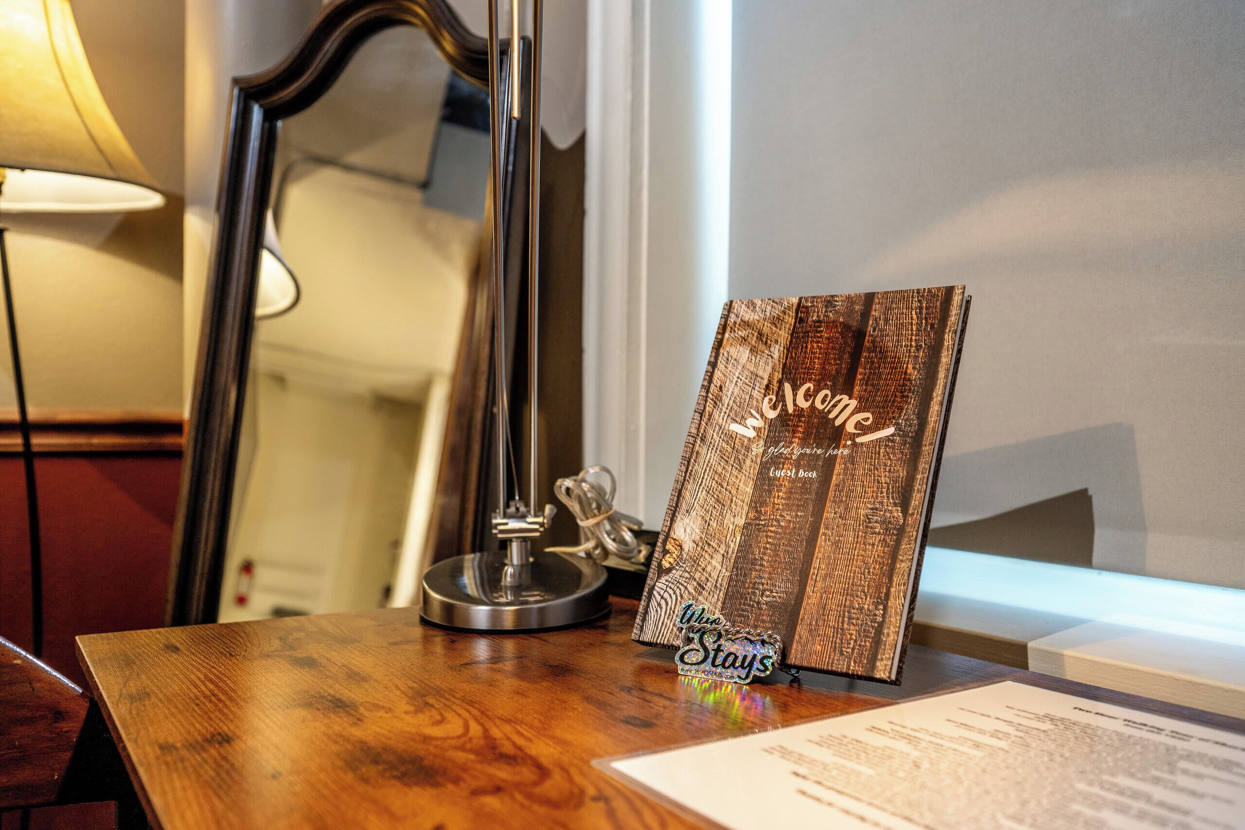 A wooden table with a framed welcome sign, a lamp, and a small decorative item.