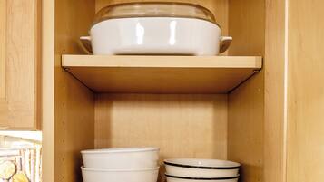 A wooden cabinet with shelves holding white bowls and plates.