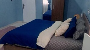 A bedroom with a bed, a wardrobe, and a door. - SNS Apartments (Adentan)
