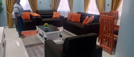A living room with two black sofas, a coffee table, and a wooden chair.
