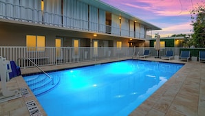 Et hotel med swimmingpool, flere balkoner og havudsigt i solnedgang.