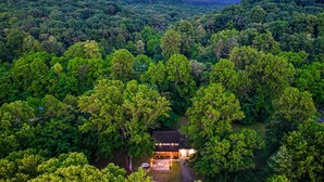 Un refugio aislado rodeado de un bosque denso, con una vista despejada de las montañas al fondo.