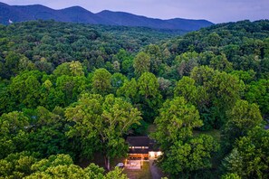 A secluded lodge surrounded by dense forest, with a clear view of the mountains in the background. - Peaceful Riverfront Gem + SNP Mountain Magic w/ Hot Tub & 6-8 Person Sauna (Shenandoah)