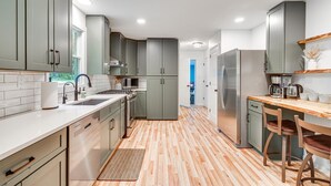 Una cocina moderna con armarios grises, un refrigerador de acero inoxidable y una mesa de comedor de madera.