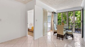 Quarto espaçoso com área de refeições, uma cama e vista através de grandes janelas.