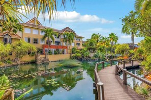 A resort with a water feature, a wooden deck, and tropical vegetation. - The Lakes Escape—Resort Living by Botanic Gardens (Cairns North)