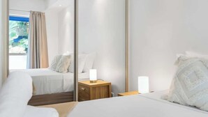 Quarto de hotel com cama, mesas de cabeceira, um espelho e vista para o exterior.