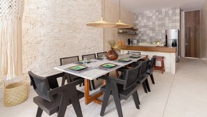 Un comedor con una mesa blanca, sillas negras y una lámpara colgante de tejido.