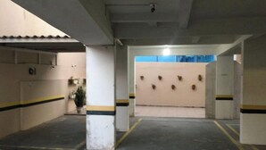 Eine Parkgarage mit Betonpfeilern, gelb-schwarz gestreiften Markierungen und einem blauen Fenster im Hintergrund.