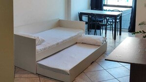 Ein gemütlicher Raum mit einem Bett, einem Esstisch mit Stühlen, einem Deckenventilator und einem Fenster mit Vorhängen.