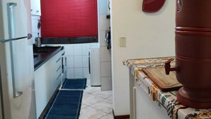 Eine Küche mit weißen Schränken, einem roten Fensterrollo, einem roten Backofen und einem großen, braunen Wasserspender.