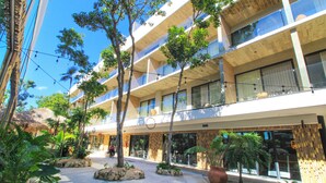 A modern hotel with multiple balconies, outdoor seating areas, and tropical landscaping. - Tuk Viento PH with Private Pool (Tulum)