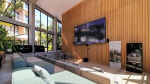 A modern lounge area with a large flat-screen TV mounted on a wooden wall, seating arrangements, and a sign for 'Hacienda'. - Tuk Viento PH with Private Pool (Tulum)