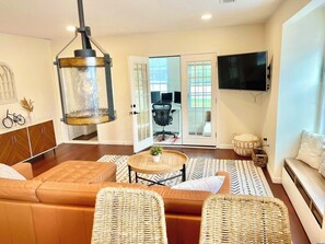 A modern living room with a sofa, wicker chairs, a coffee table, and a television. - Beautiful 3 BR Home by the Water- Family Friendly (Weymouth)