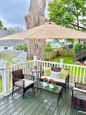 A covered outdoor seating area with wicker furniture, a glass table, and a bench. - Beautiful 3 BR Home by the Water- Family Friendly (Weymouth)